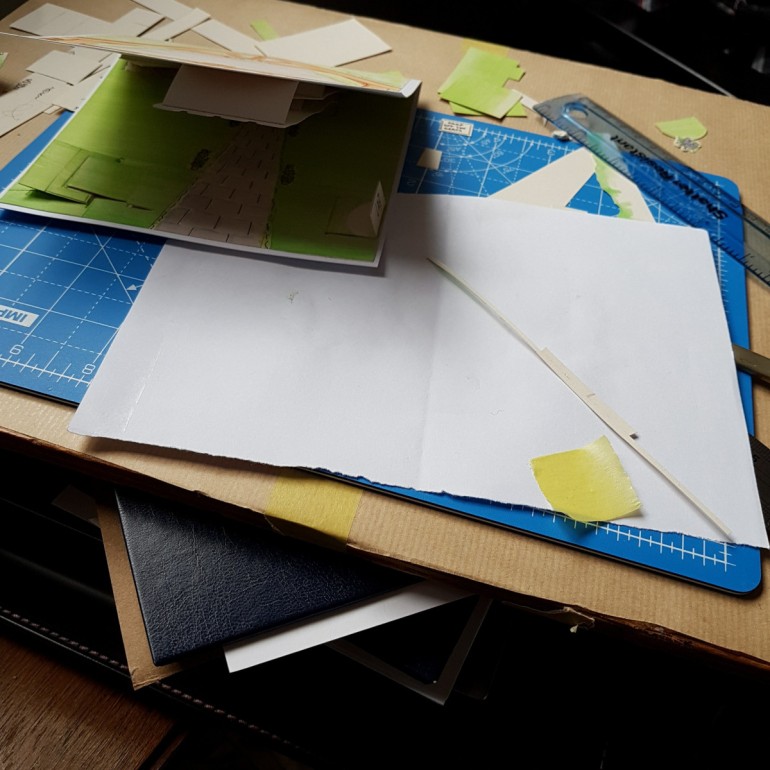Pieces of cut paper, ruler and a card you can't quite see on a small cutting mat